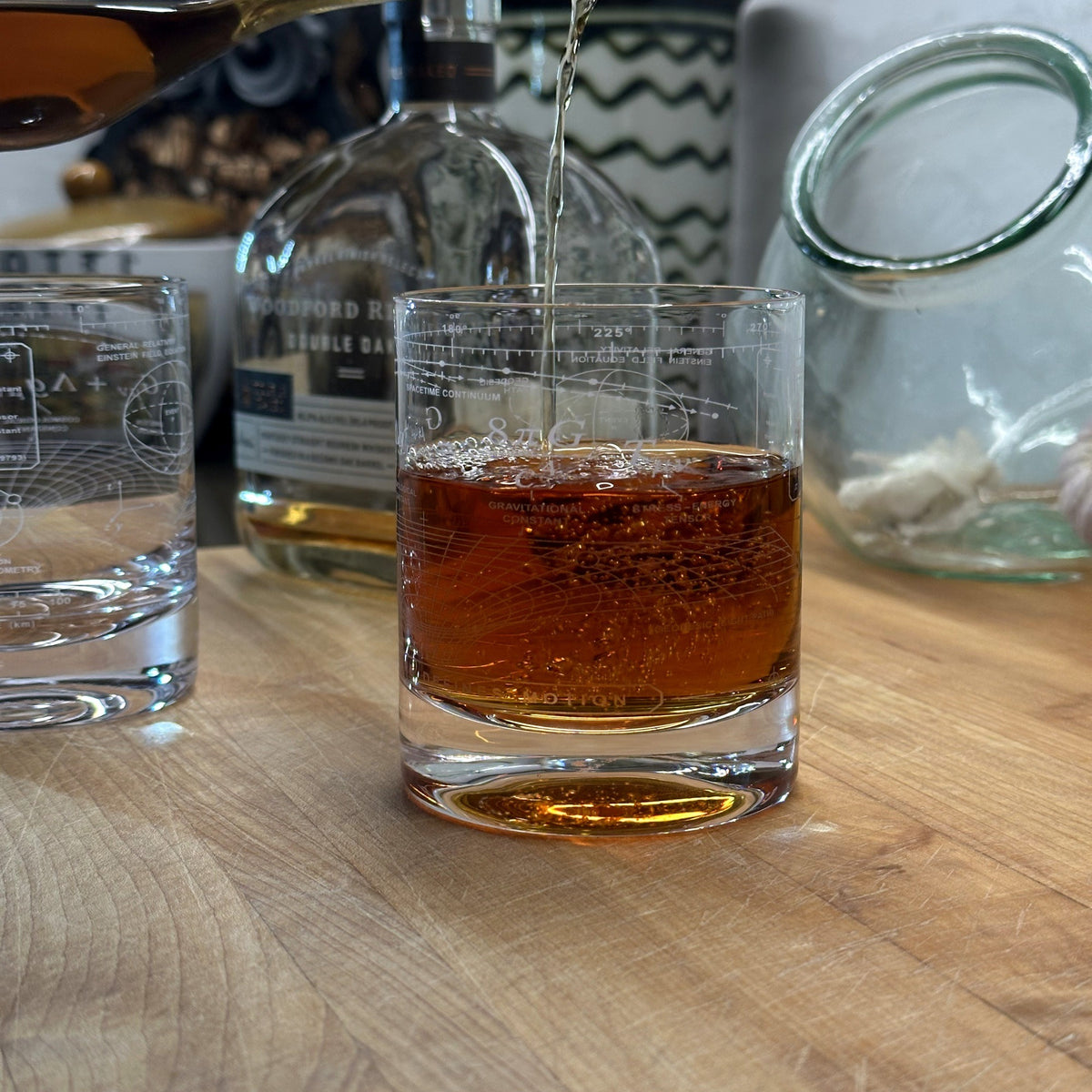 Whiskey being poured into a Vector Einstein Field Equation engraved crystal rocks glass